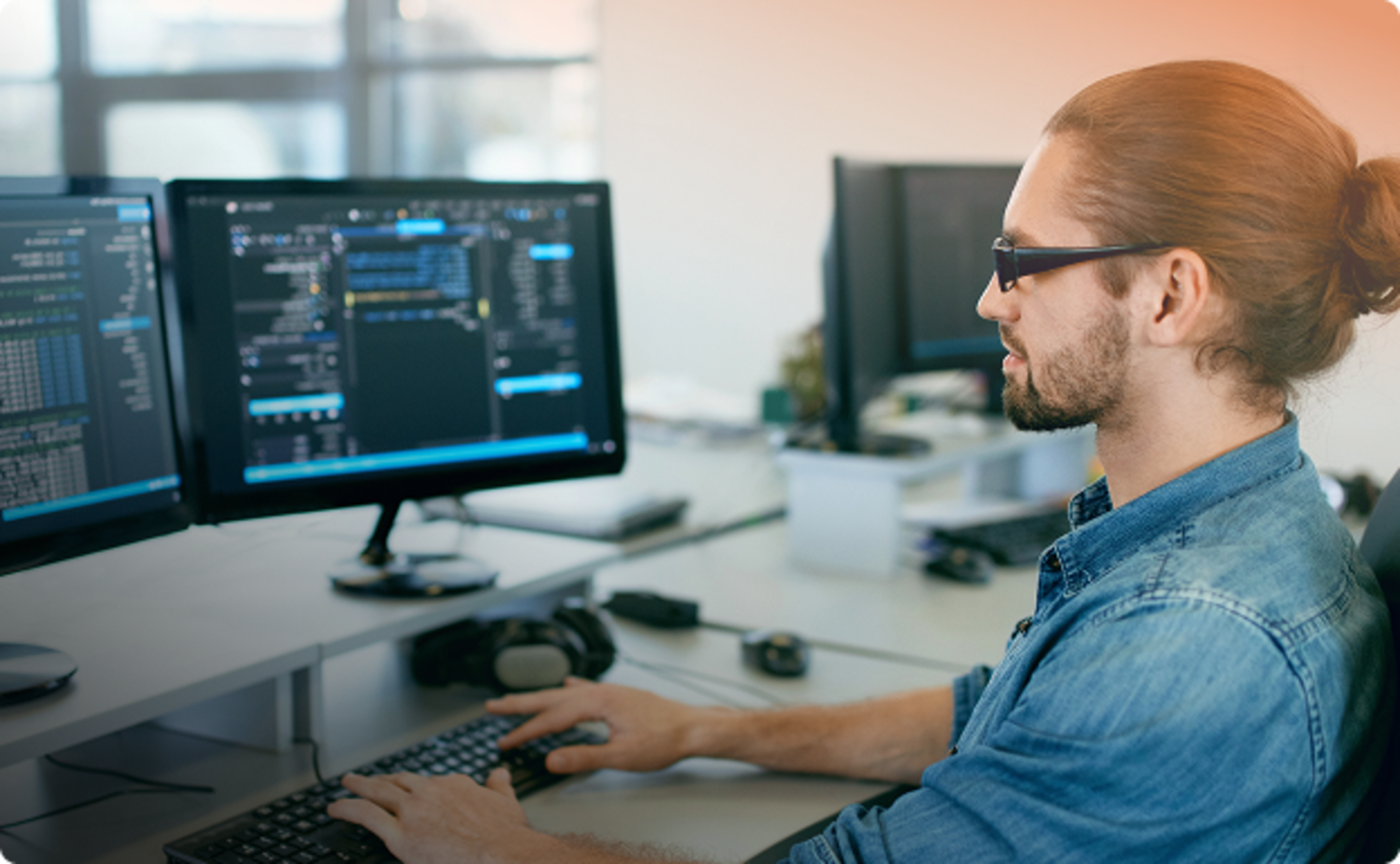 Ein junger Mann sitzt am Schreibtisch und arbeitet an einem Computer